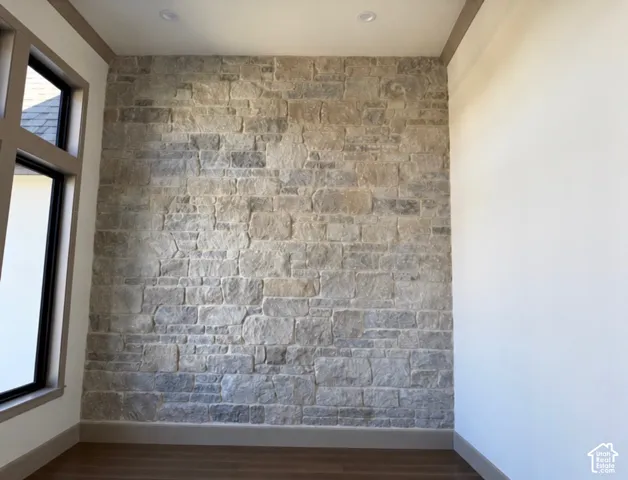 Stone accent wall with recessed lighting, wood-finish flooring, and a large window