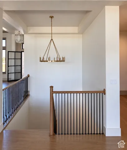 Wood-finish flooring, recessed ceiling detail, and a brass-tone chandelier