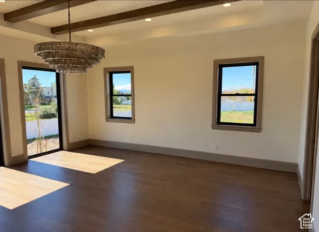 Wood-finish flooring, exposed ceiling beams, recessed lighting, and a tiered chandelier