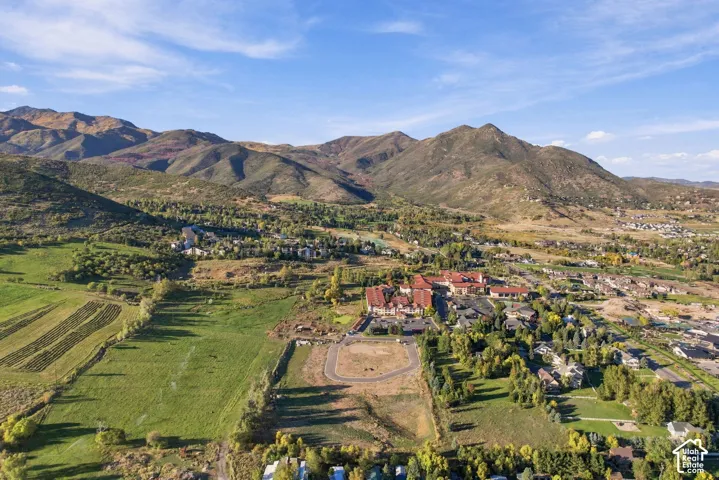 Expansive mountain landscape with diverse terrain, including lush green fields, wooded areas, and developed residential sections