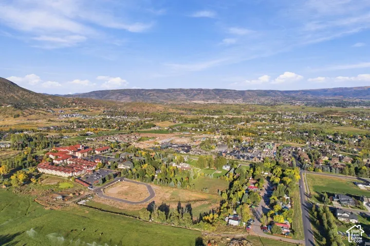 Expansive land parcel within a developed community, framed by surrounding mountains and trees