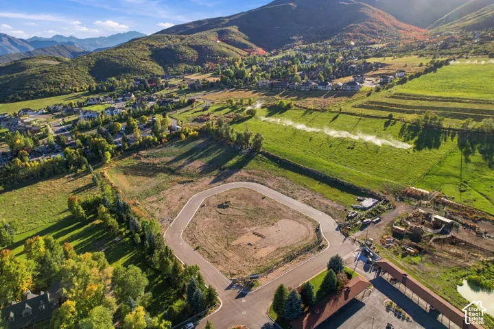 Expansive mountainous backdrop framing a developing residential area with paved streets and surrounding green spaces