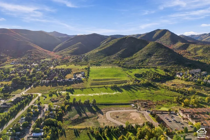 Expansive mountain range backdrop, established residential areas, large undeveloped land parcels, and mature tree coverage