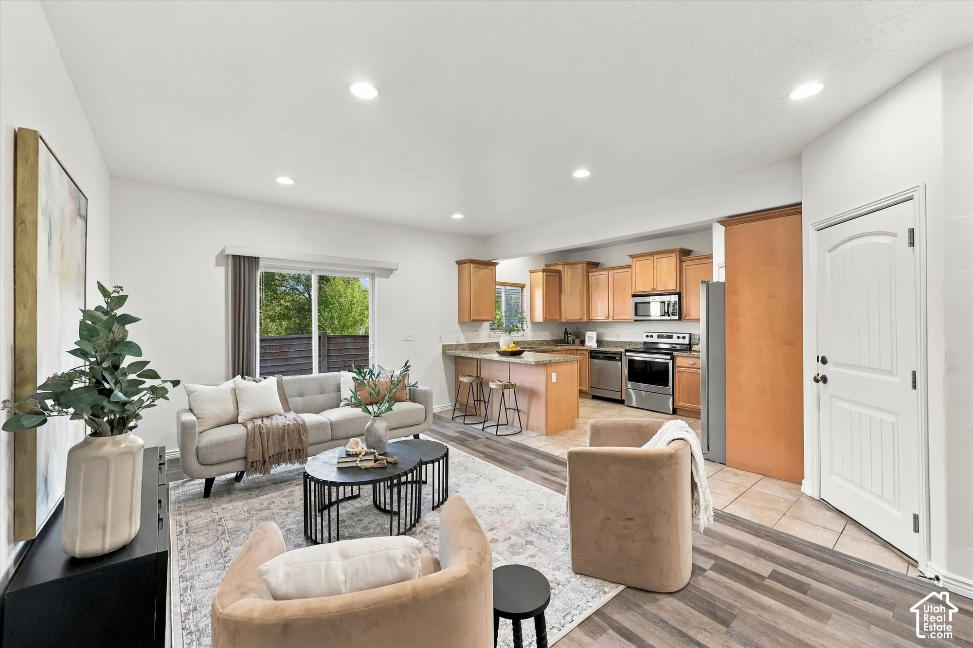 Open-concept living area with wood-finish flooring, recessed lighting, and a sliding glass door to back patio