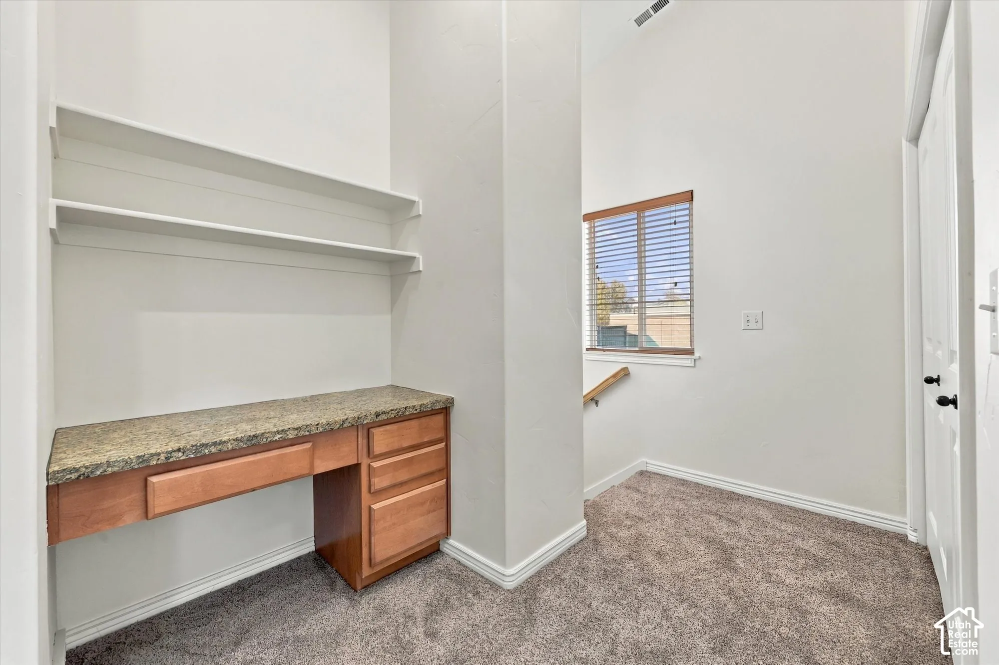 Built-in desk with wood cabinetry, accompanied by upper shelving