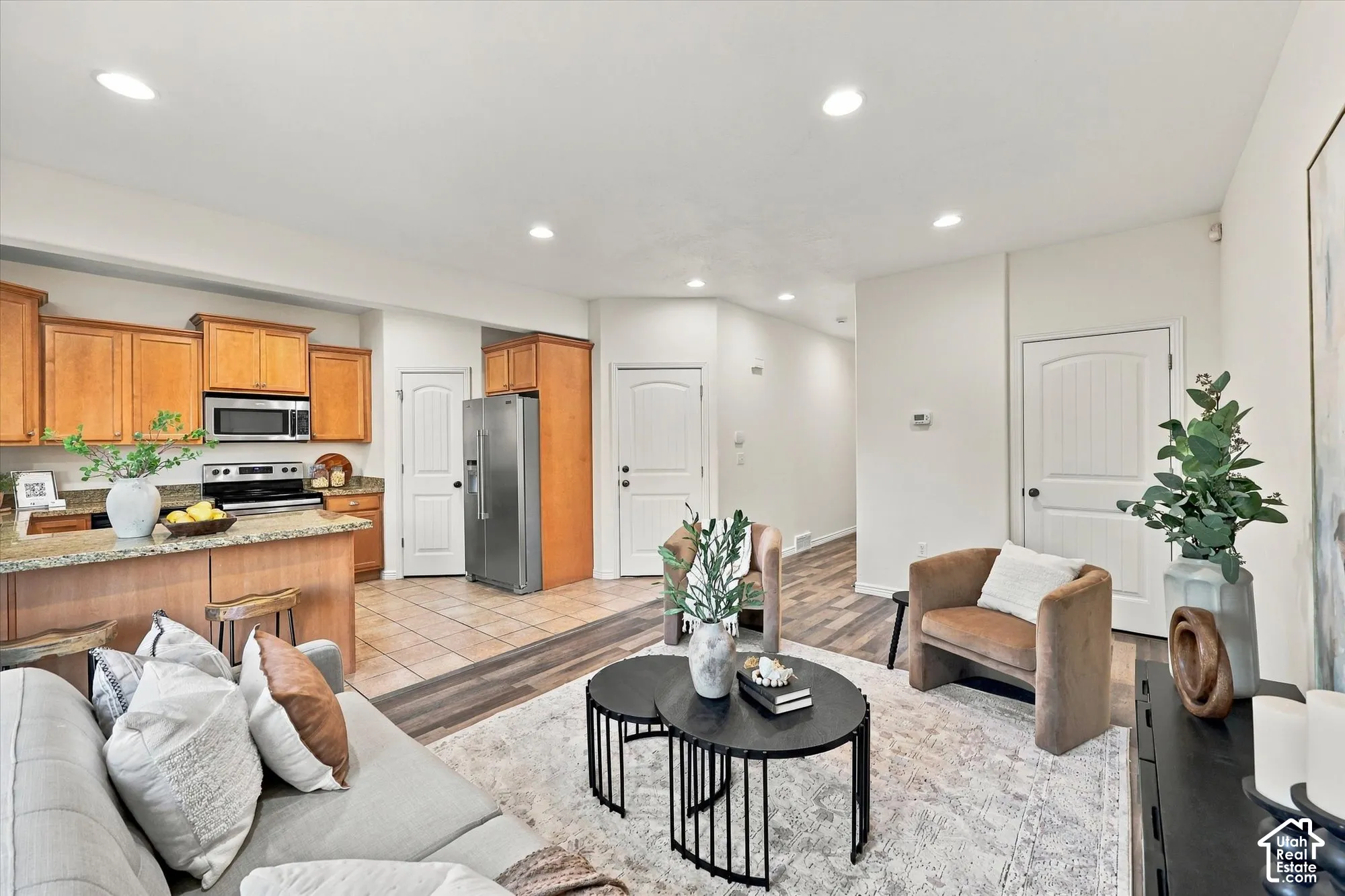 Open living area and kitchen. Recessed lighting throughout, LVP flooring, breakfast bar, stainless steel appliances, and wood cabinetry