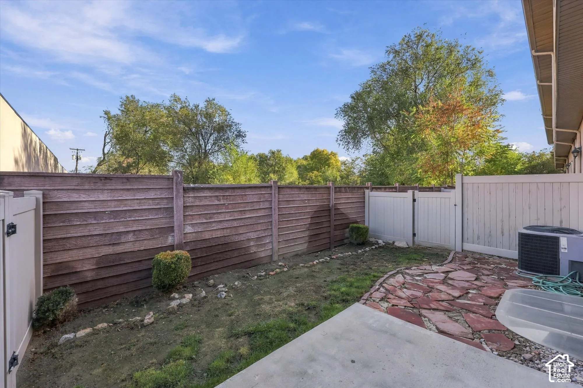 Fenced backyard, private outdoor space featuring a concrete patio and stone pavers