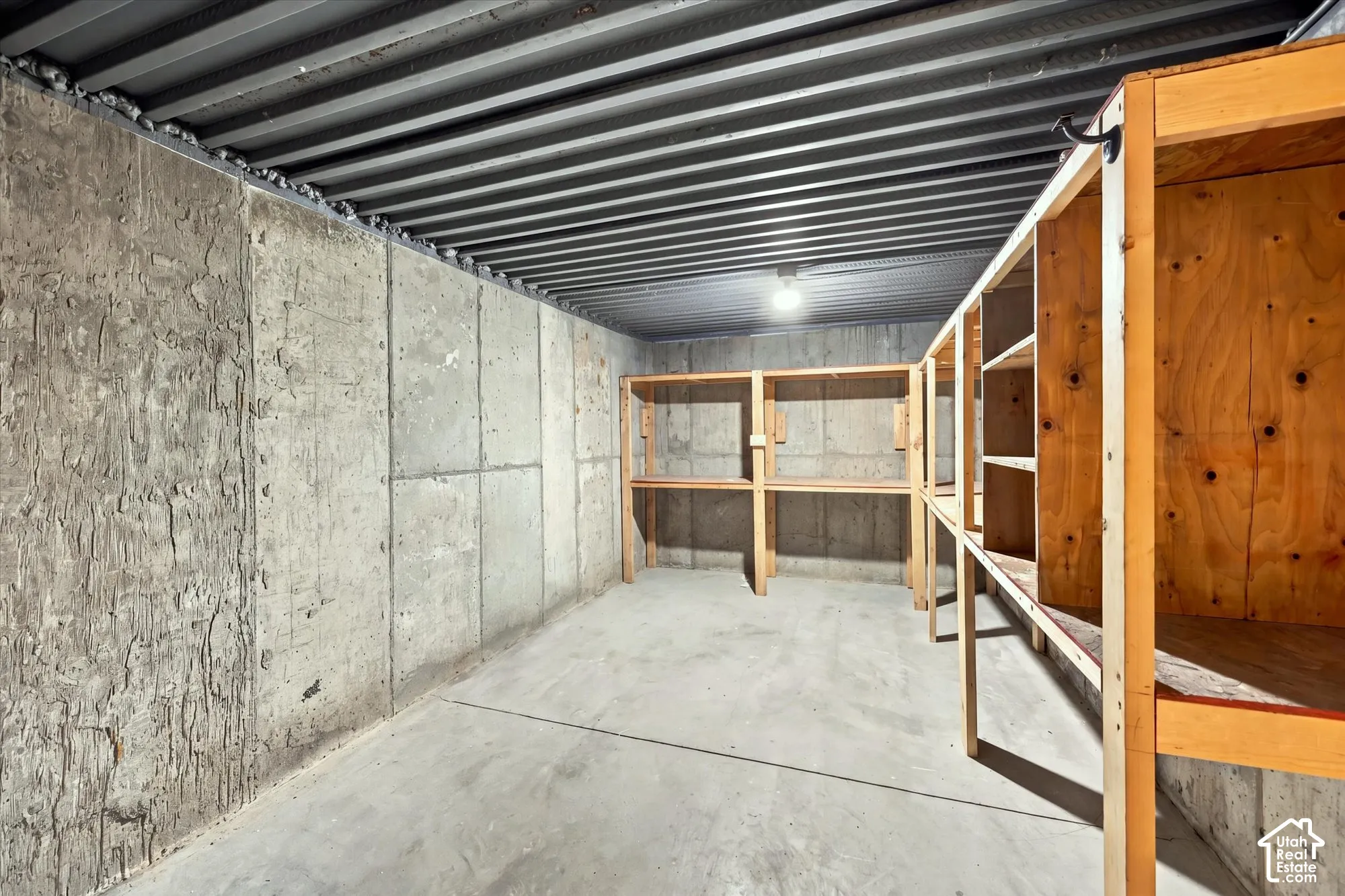 Concrete flooring with exposed concrete walls and built-in wooden shelving