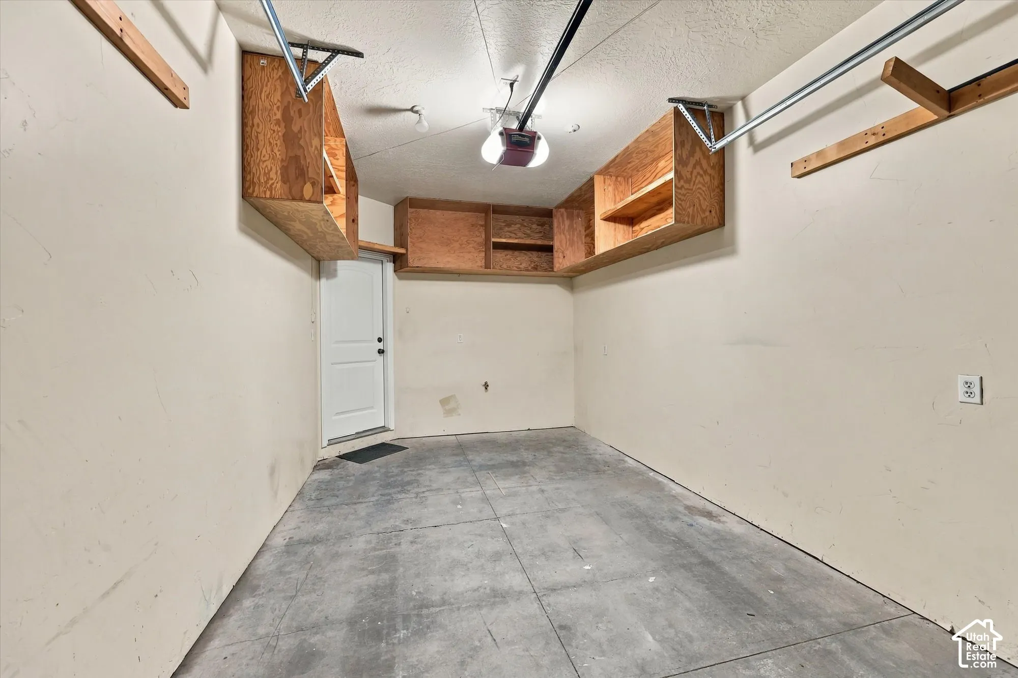 Garage with concrete flooring, overhead wood-finish cabinetry providing extra storage