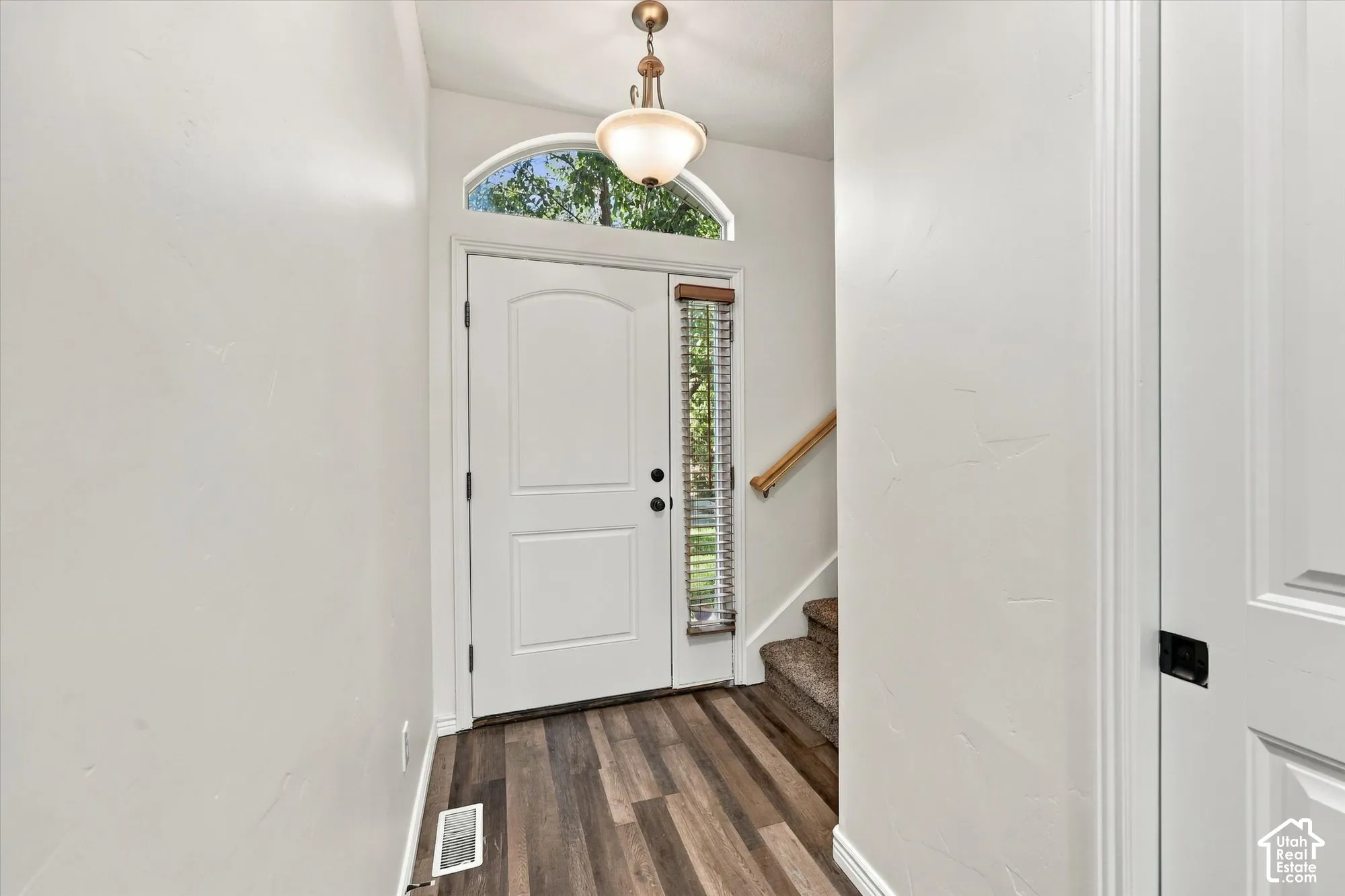 Entryway featuring LVP flooring, a white paneled door with an arched transom, and a drum pendant light fixture