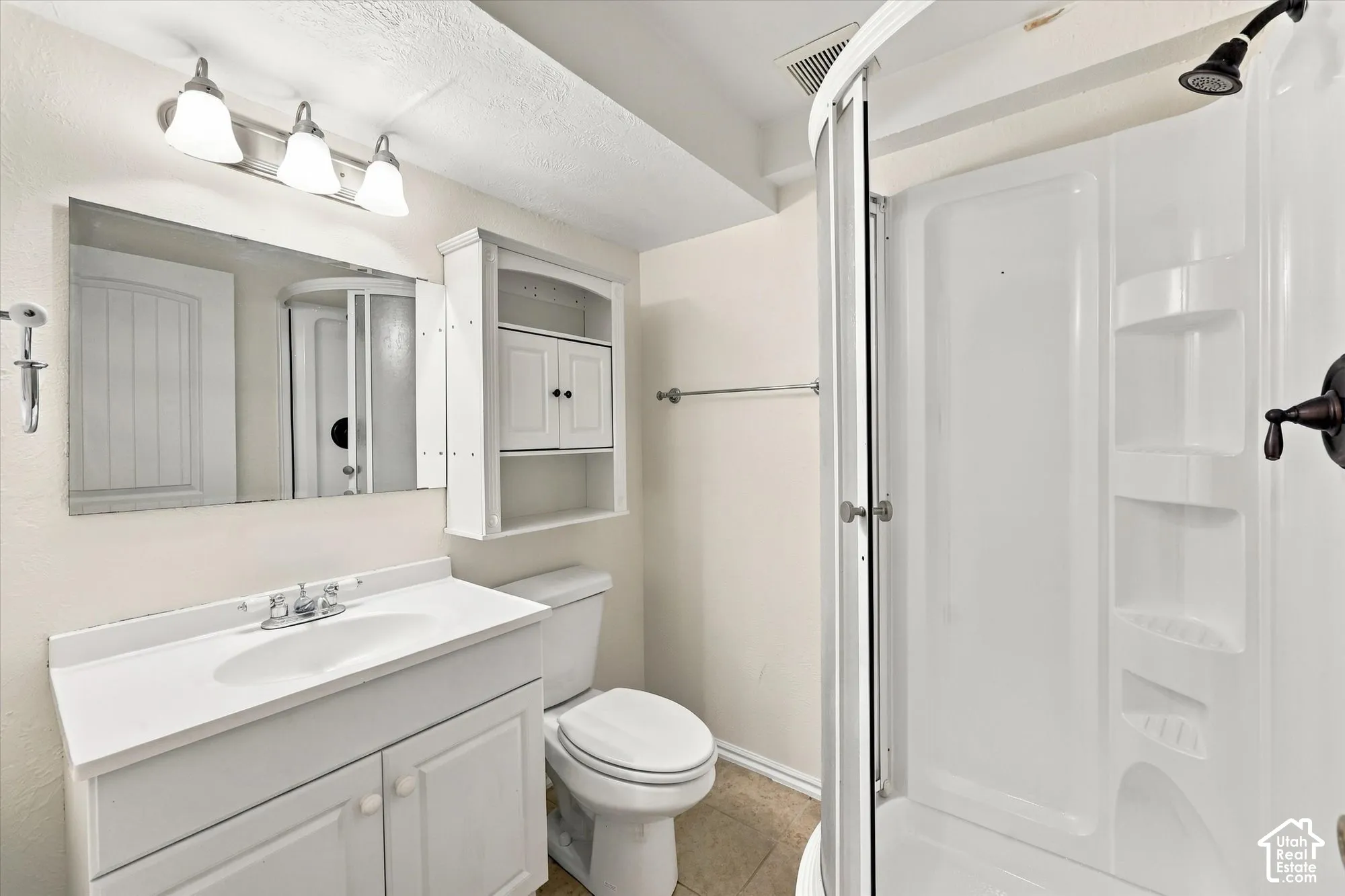 White vanity with integrated sink, rectangular mirror, and three-light fixture