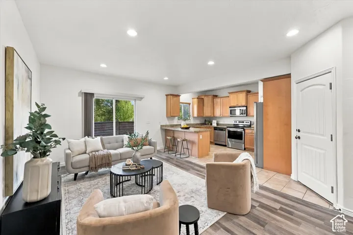 Open-concept living area with wood-finish flooring, recessed lighting, and a sliding glass door to back patio