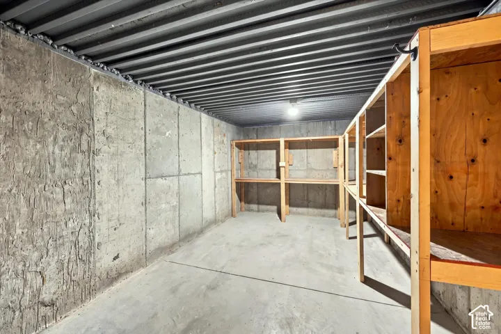 Concrete flooring with exposed concrete walls and built-in wooden shelving