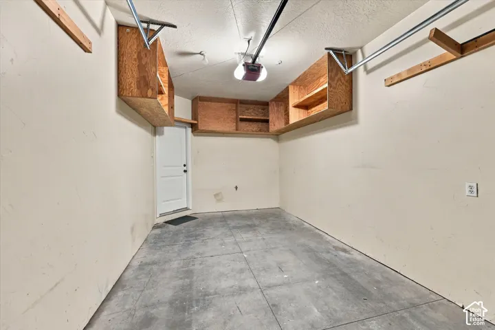Garage with concrete flooring, overhead wood-finish cabinetry providing extra storage