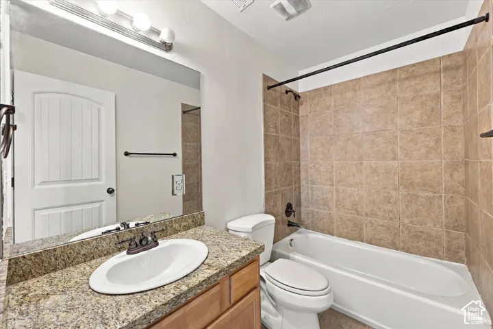 Bathroom featuring a vanity with an oval undermount sink, granite-style countertop, and wood-finish cabinetry