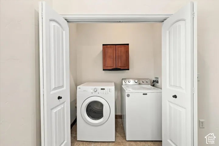 Dedicated laundry area featuring a wall-mounted wood-finish cabinet and tile flooring