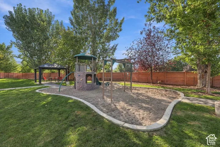 Community playground with a climbing structure and swings, a covered gazebo, and mature trees