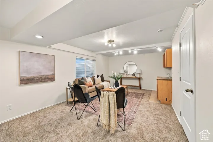Carpeted living area with recessed lighting, a built-in wet bar featuring wood cabinetry, and a window with blinds