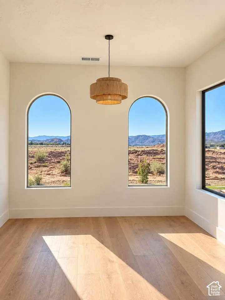 Arched windows featuring natural mountain and desert scenery, wood-finish flooring, and a tiered woven-texture pendant light fixture
