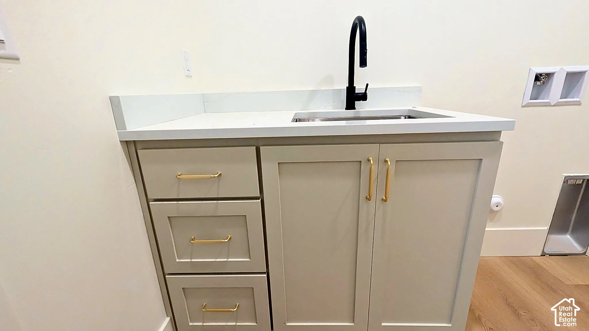 Shaker-style cabinetry with brass hardware, solid surface countertop, undermount sink, and matte black high-arc faucet