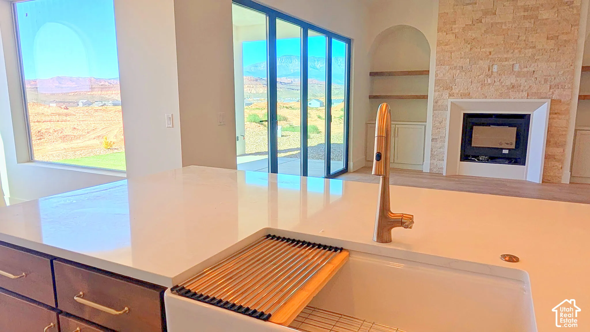 Kitchen island featuring a white countertop, farmhouse-style sink, and a high-arch metallic faucet
