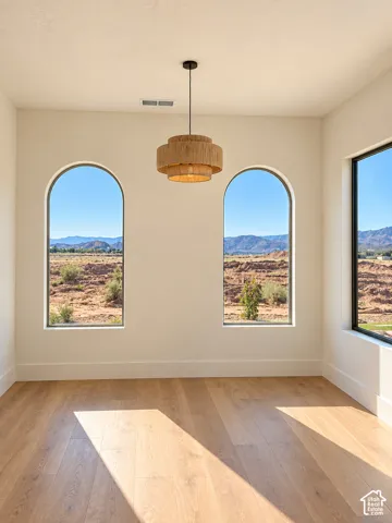 Arched windows, modern chandelier, wood-finish flooring, white walls, desert landscape