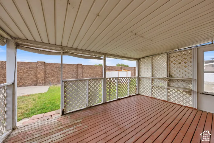 Covered patio with wood-finish flooring, lattice railing, and a paneled ceiling