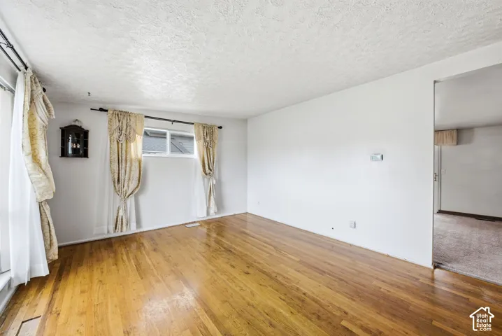 Hardwood flooring throughout, white painted walls, and textured ceilings