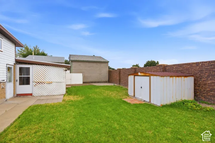 Expansive lawn, brick wall, private patio area, and storage shed