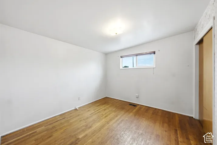 Wood-finish flooring, white painted walls, and a single window with blinds