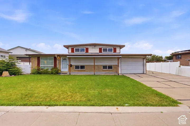 Mid-century modern exterior featuring a two-car garage, elongated driveway, and a front lawn