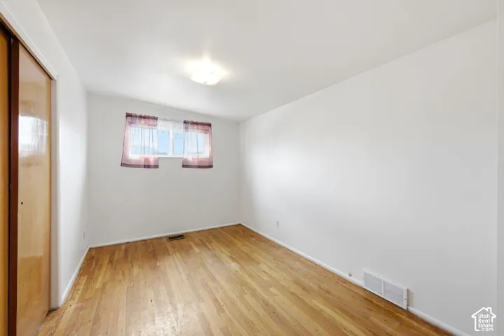 Wood-finish flooring with white walls and a ceiling-mounted light fixture