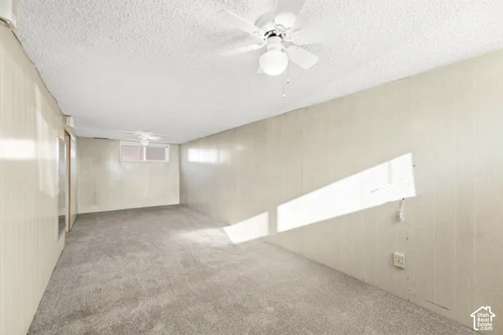 New carpet, textured ceiling, recessed window, wall-mounted ceiling fan, and grey carpeting
