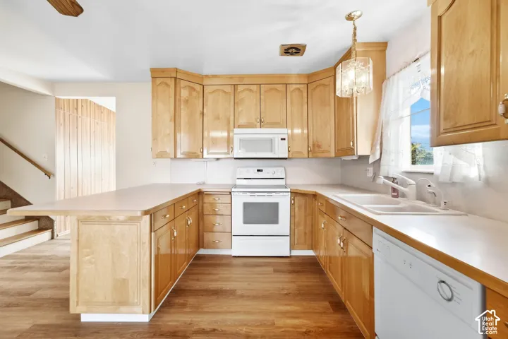 U-shaped kitchen featuring wood-finish cabinetry, white appliances, and wood-finish flooring
