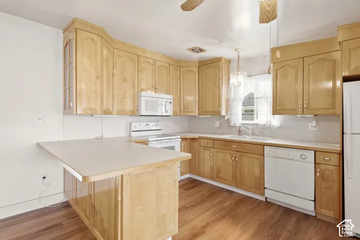 Expansive kitchen featuring wood-finish cabinetry, white appliances, durable countertops, and wood-finish flooring