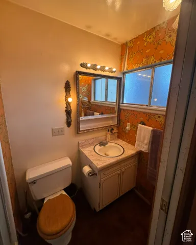 Vanity with integrated sink, patterned wallpaper, wall-mounted mirror, and decorative light fixtures