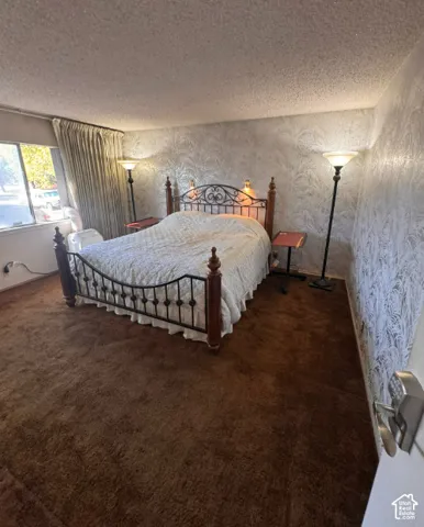 Textured wallpaper accents, wall-to-wall carpeting, and a window with curtain treatments