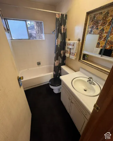 Bathroom featuring a white bathtub, white tiled shower surround, toilet, and vanity with an integrated sink