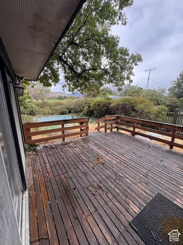 Expansive wood deck with wood railings, featuring a verdant landscape backdrop