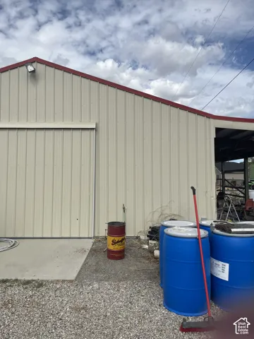 Metal siding structure with a red trim roofline and a large roll-up door