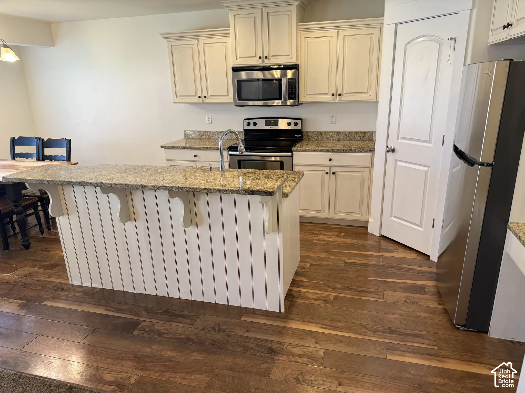 Kitchen featuring a central island with a granite countertop, white paneled base, and decorative corbels
