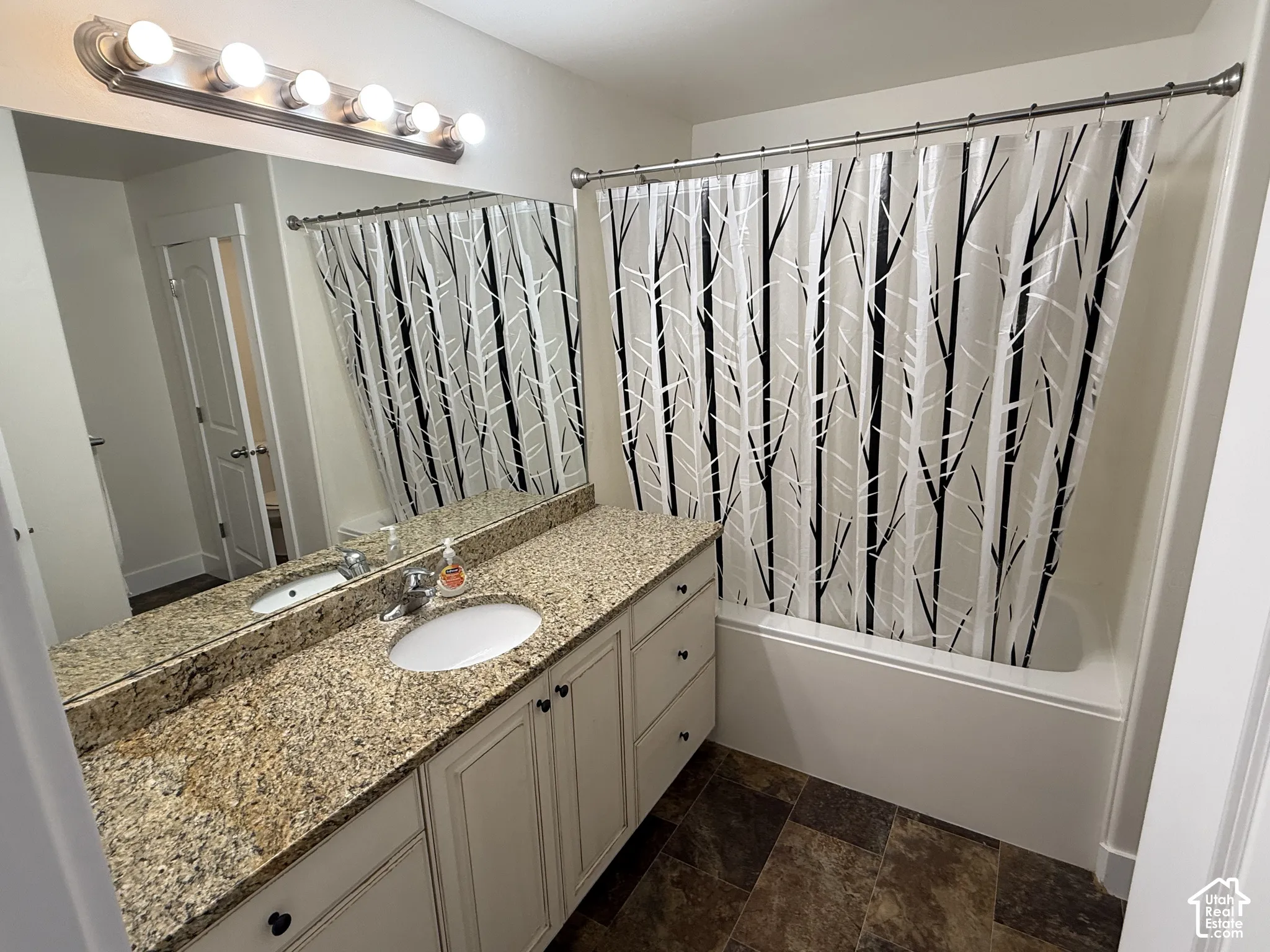 Dual vanity with granite countertop, integrated sink, and white cabinetry