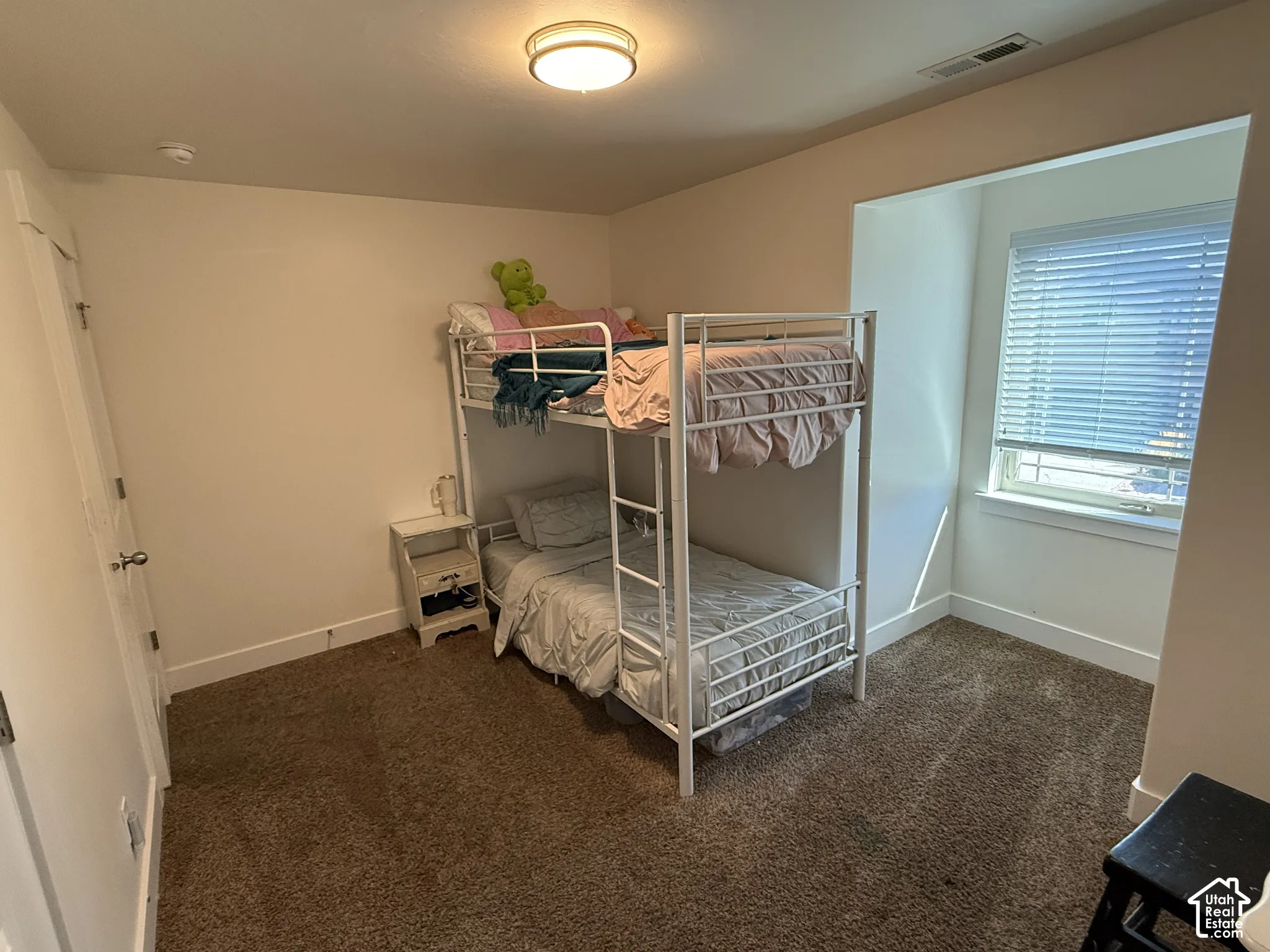 Recessed window alcove with horizontal blinds, overhead ceiling light fixture, and brown carpet flooring