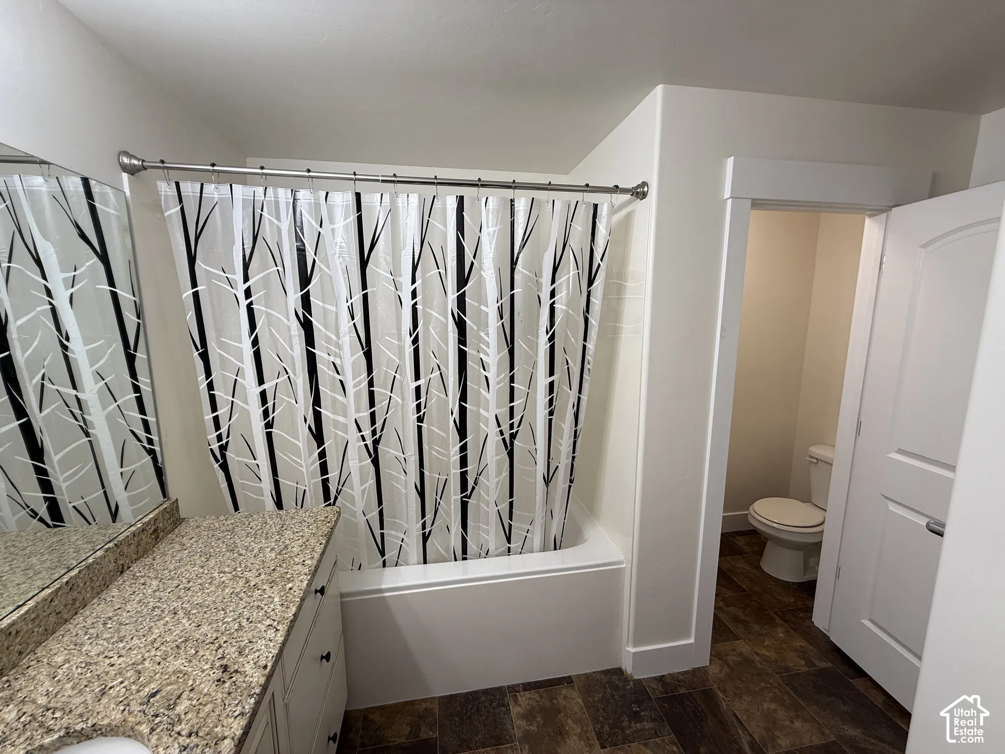 Bathtub with shower, white vanity with granite-style countertop, integrated sink, and wood-finish flooring