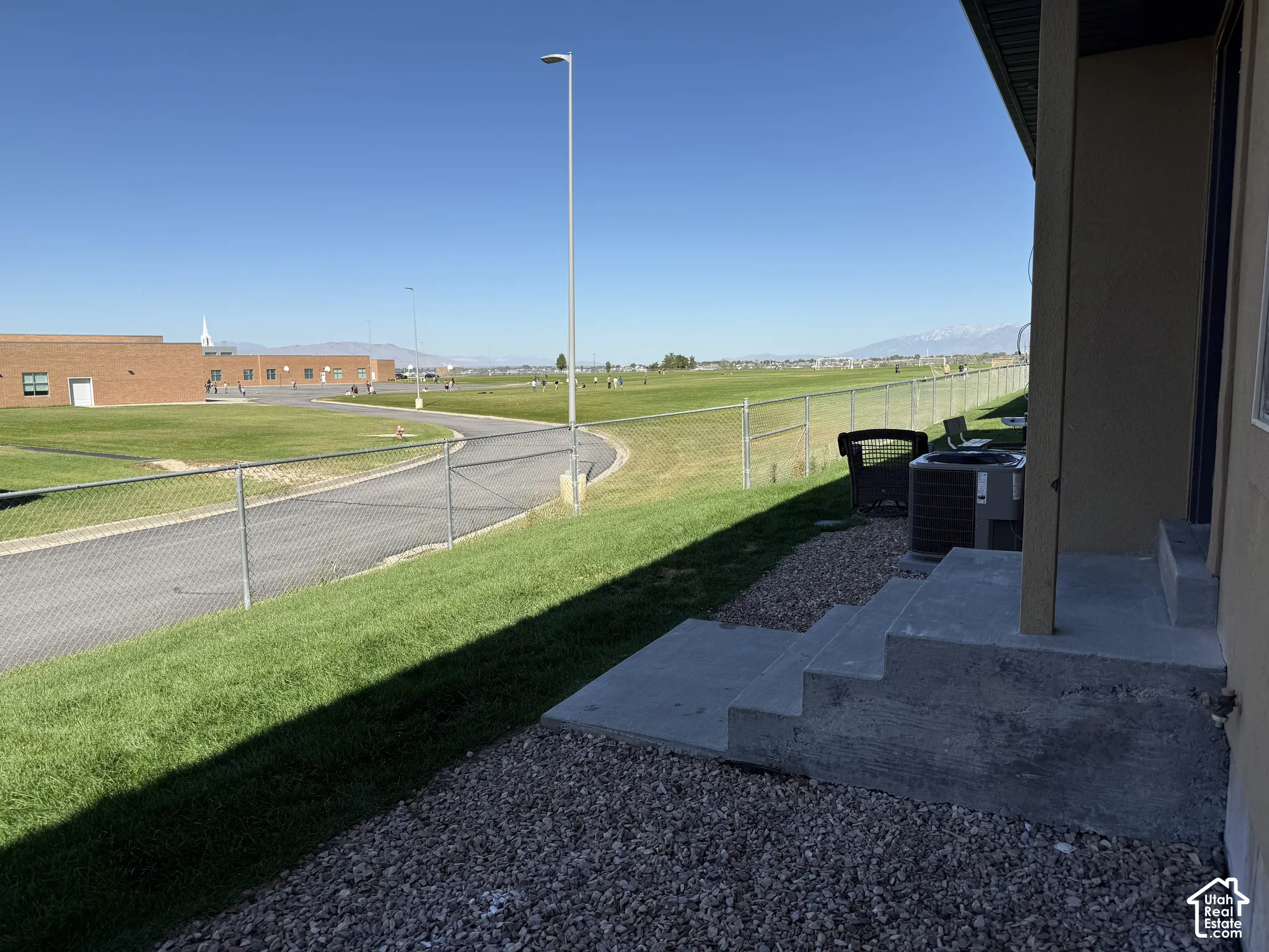 Concrete steps with gravel landscaping, chain link fencing, and expansive green space