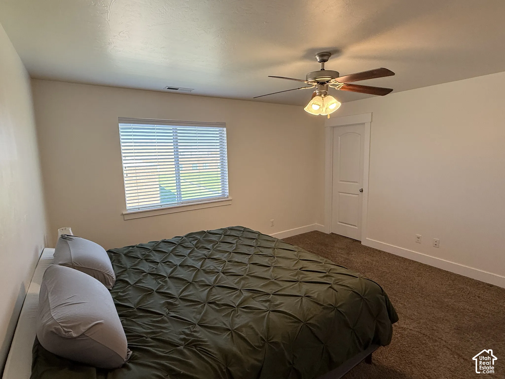 Carpeted flooring, ceiling fan with light fixture, window with blinds, and a white interior door with trim