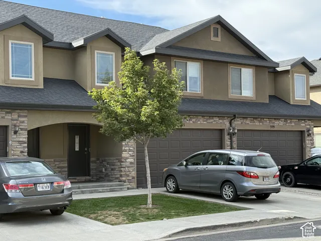 Two-story exterior with stucco finish and stone accents, featuring a multi-car garage with individual doors, and multiple windows with white trim