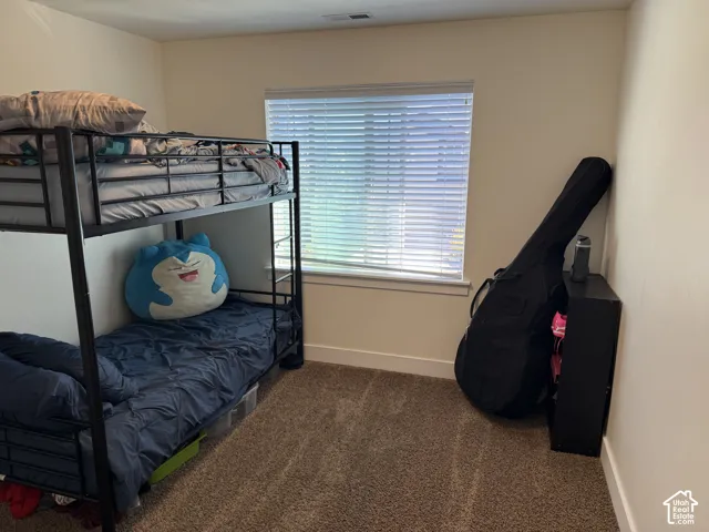 Carpeted flooring, neutral wall color, and a window with horizontal blinds