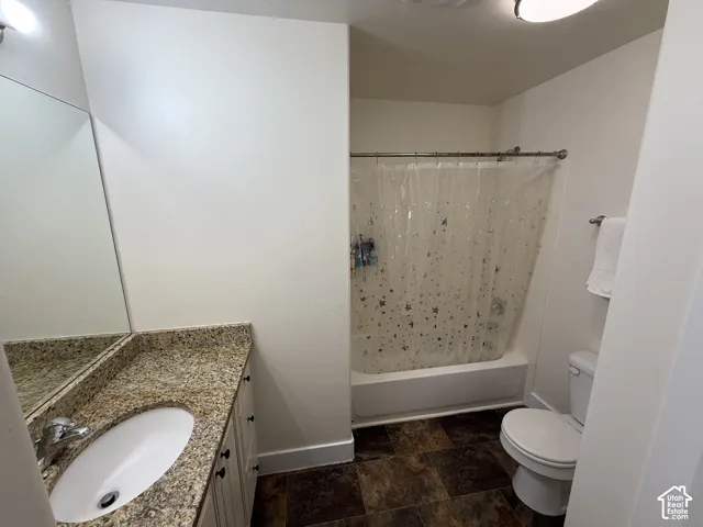 Bathroom featuring a vanity with a granite-style countertop, undermount sink, and a shower-over-tub combination