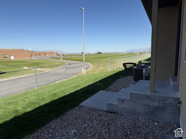 Concrete steps with gravel landscaping, chain link fencing, and expansive green space